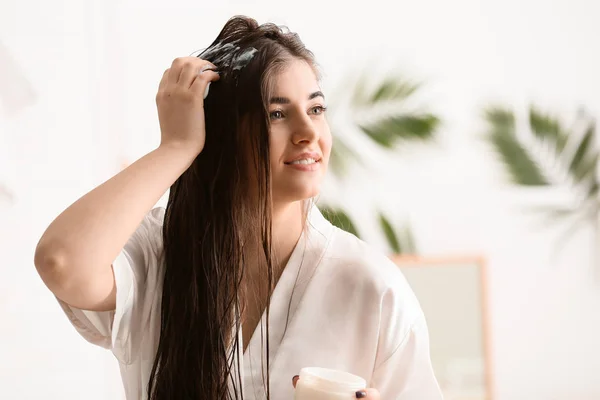 年轻女子在浴室里对美丽的长发涂上奶油 — 图库照片