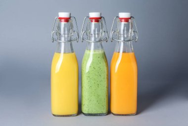 Gri arka plan üzerinde sağlıklı meyve suları şişe