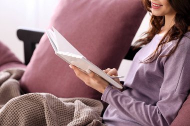 Evde kitap okuyan güzel genç bir kadın.