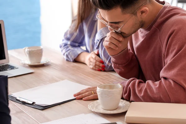 Young couple reading insurance contract in cafe