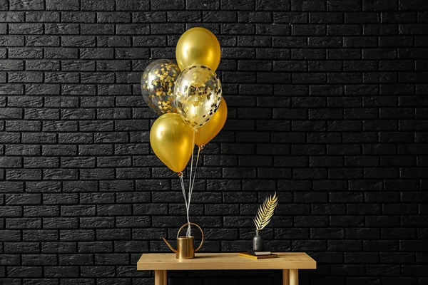 Table with decor and balloons near dark brick wall