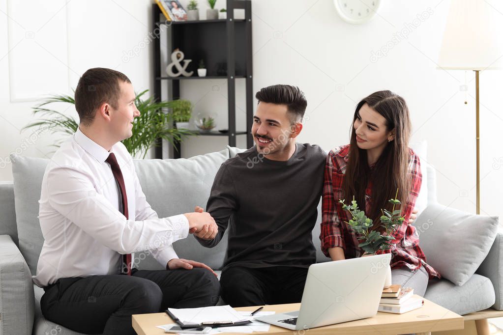 Young couple concluding agreement with insurance agent at home