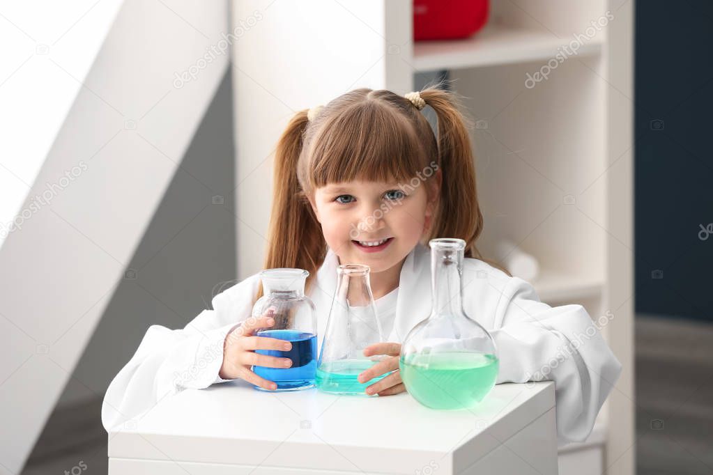 Cute little girl dressed as laboratory worker playing at home