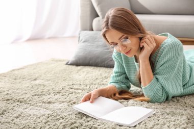 Evde kitap okuyan güzel genç bir kadın.