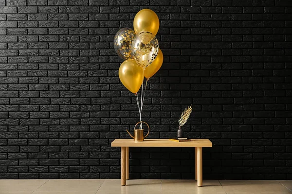 Table with decor and balloons near dark brick wall
