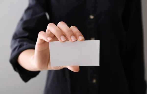 Young woman with blank business card, closeup