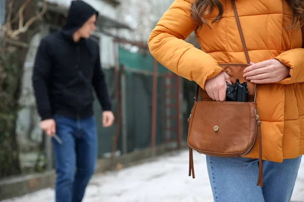 Woman taking pistol out of her bag in order to protect herself against thief
