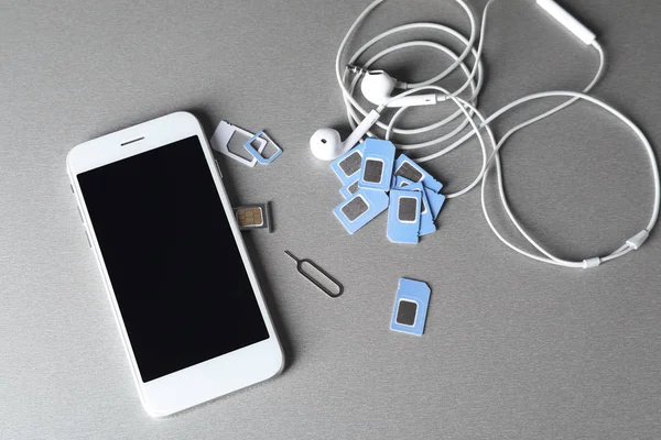Mobile Phone Sim Cards Earphones Grey Background — Stock Photo, Image