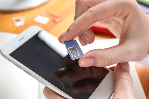 Woman with sim card and mobile phone, closeup