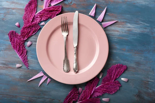 Beautiful table setting and cabbage leaves on wooden background