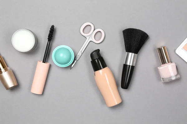 Set of makeup cosmetics with accessories on grey background