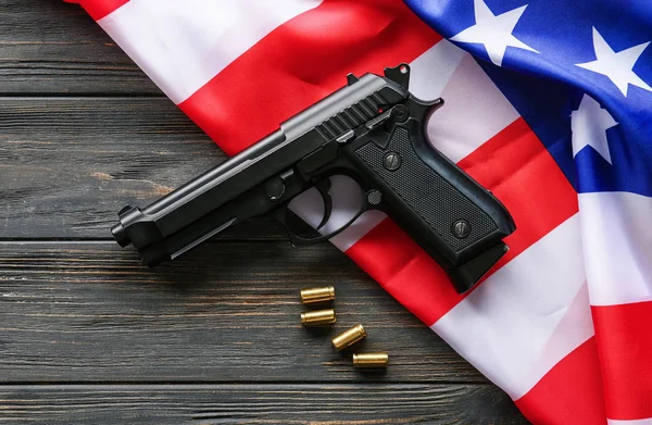 Pistol, bullets and USA flag on wooden background