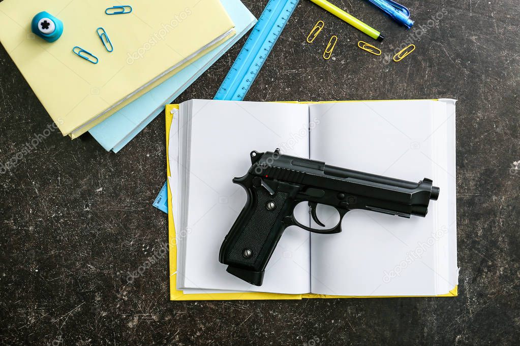 Pistola y papelería sobre fondo oscuro. No hay armas en la escuela 2024