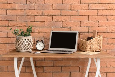 Tuğla duvarının yakınında modern dizüstü bilgisayar ile rahat çalışma alanı