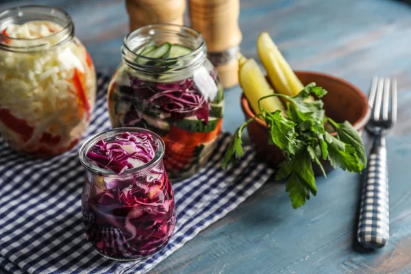 Glass jars with fermented vegetables on wooden table