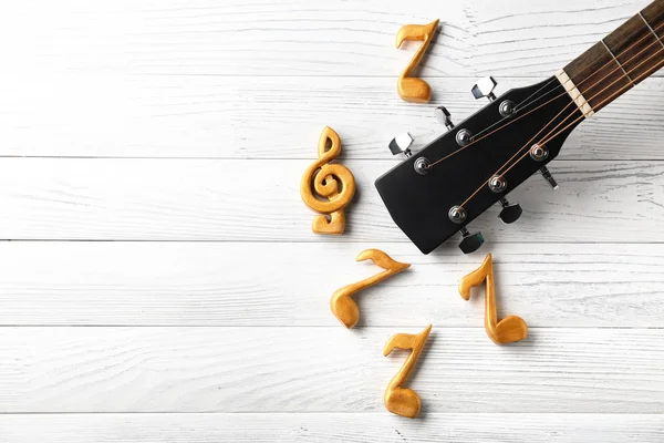 Guitar and music notes on white wooden background