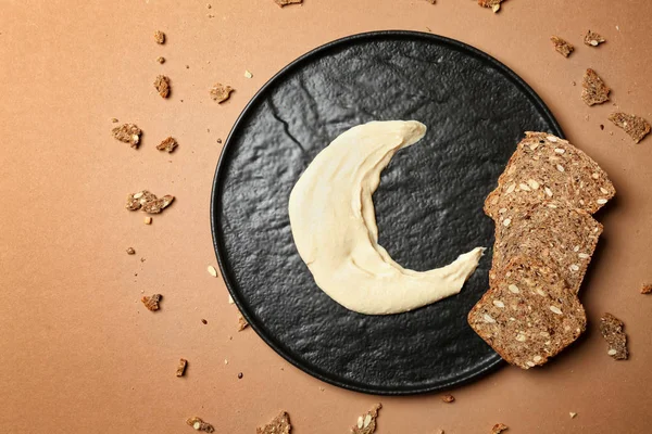 Plate with bread and half-moon made of cream as symbol of Islam on color background