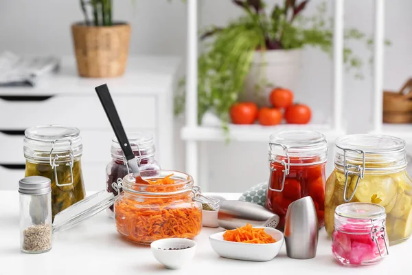 Glass jars with fermented vegetables and spices on table in kitchen