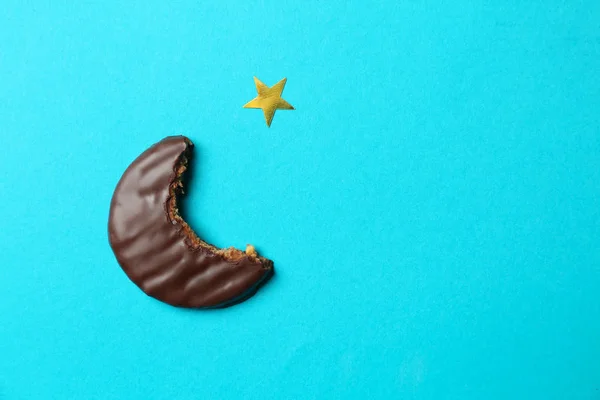 Bitten cookie in shape of half-moon as symbol of Islam on color background