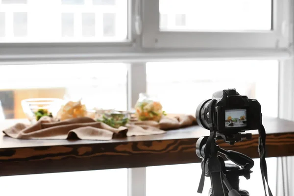 Professional photo camera near composition of food on table in studio