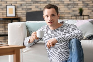 Yakışıklı genç adam evde kahve içiyor.