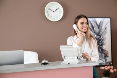 Kadın resepsiyonist otelde telefonla konuşuyor