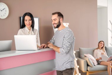 Otelin resepsiyon masası yakınındaki genç adam