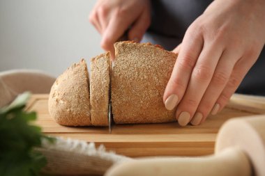 Genç kadın kesme taze ekmek masada, portre