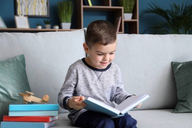 Evde kitap okuyan şirin bir çocuk.
