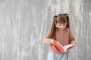 Grunge duvarının yakınında kitapla sevimli küçük kız