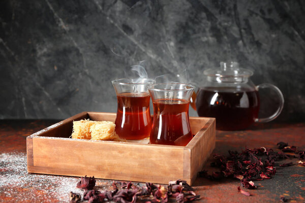 Деревянный поднос с турецким чаем в традиционных стаканах и восточными сладостями на столе

