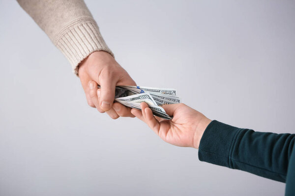 Человек дает деньги своему сыну на светлом фоне. Концепция алиментов
