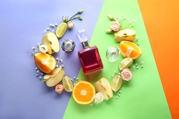 Composition with bottle of perfume, fruits and flowers on color background