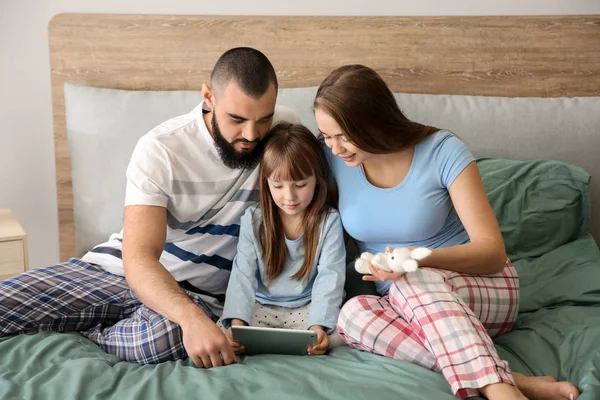 Happy family with tablet computer on bed at home