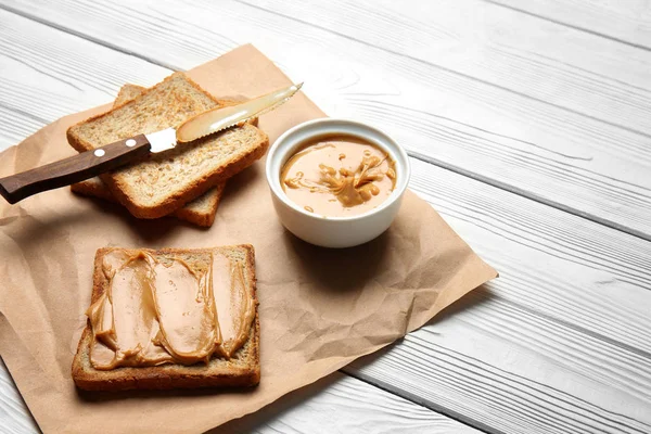 Pão Torrado Com Manteiga Amendoim Saborosa Mesa Madeira Branca — Fotografia de Stock