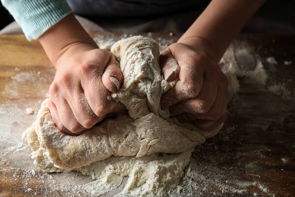 Young woman preparing dough for bread at table, closeup