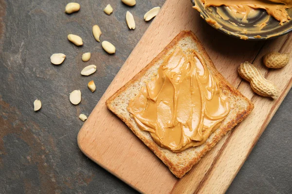 Placa Madeira Com Pão Torrado Manteiga Amendoim Saborosa Fundo Cinza — Fotografia de Stock