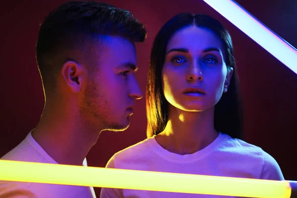 Portrait of young couple with neon lamps on dark background