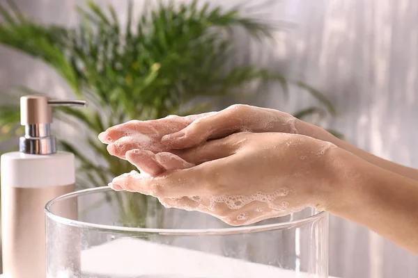 Woman washing hands with soap in bathroom