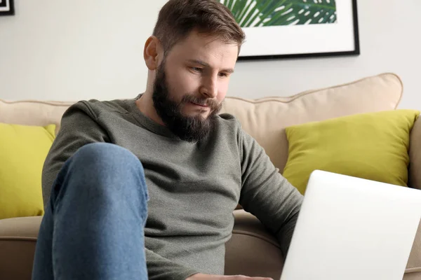 Bearded man working on laptop at home