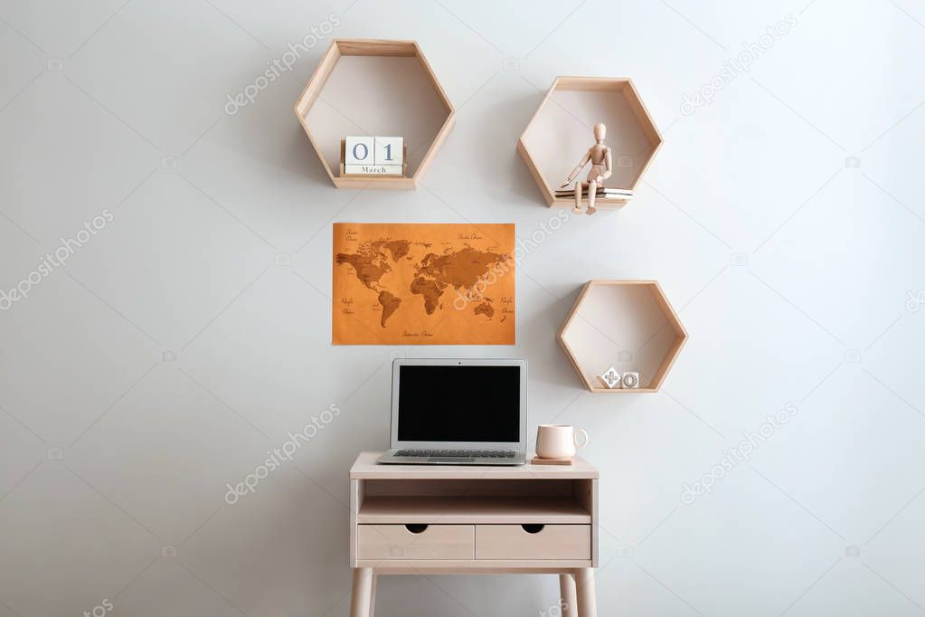 Modern home workplace with laptop near light wall in room
