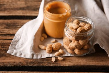 Kavanoz lezzetli fıstık ezmesi ve ahşap masa üzerinde fındık ile