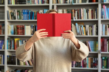 Genç kadın yüz kitap modern kütüphane arkasında saklanıyor