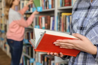 Kütüphanede kitap seçen genç bir kadın.