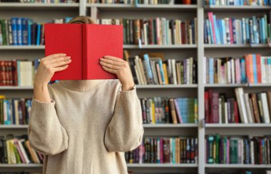 Genç kadın yüz kitap modern kütüphane arkasında saklanıyor