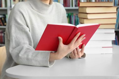 Genç kadın masada kitaplığındaki kitap okuma