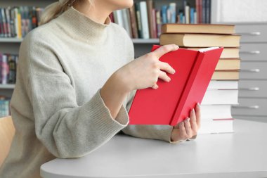 Genç kadın masada kitaplığındaki kitap okuma