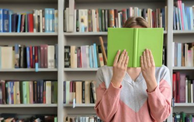 Genç kadın yüz kitap kütüphane arkasında saklanıyor