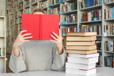 Genç kadın masada kitaplığındaki kitap okuma