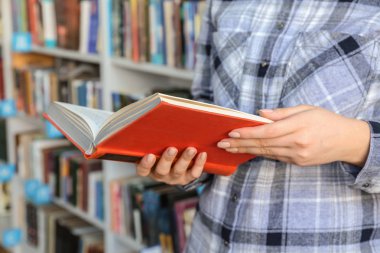 Kütüphanede kitap seçen genç bir kadın.